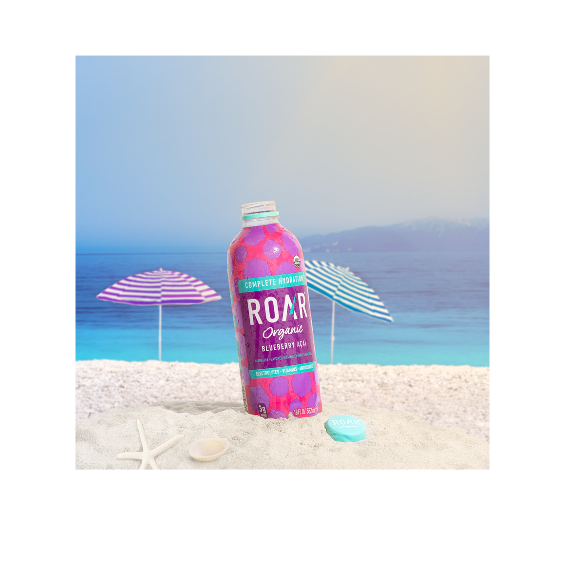 bottle of roar organic blueberry acai drink on a beach Image2