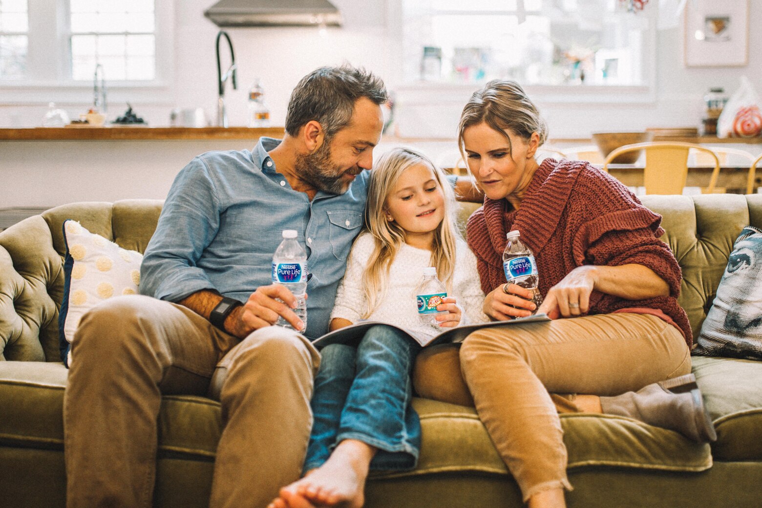 Father, daughter and mother sitting on couch drinking nestle pure life water