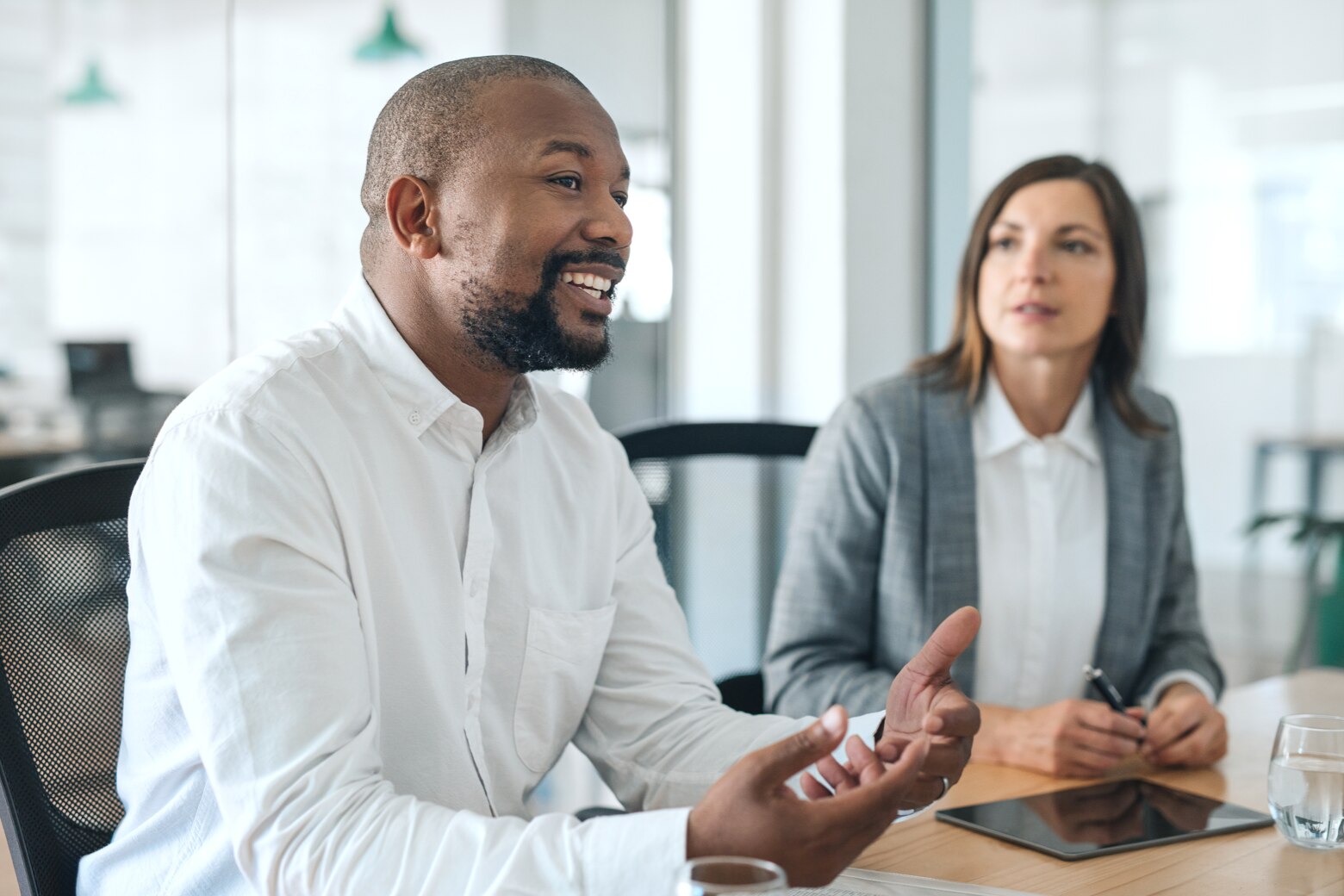 two people drinking water in an office meeting