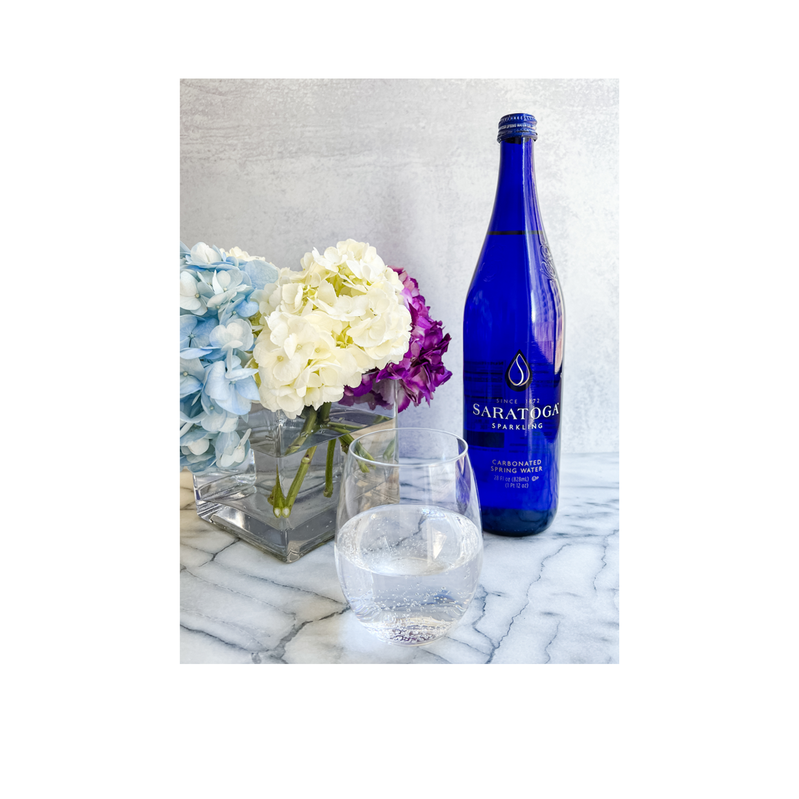 flowers in vase next to saratoga sparkling glass bottle Image2